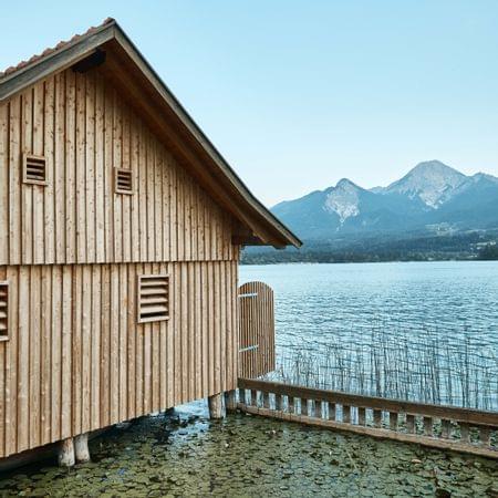 Casetta in legno sul lago con ninfee e montagne sullo sfondo